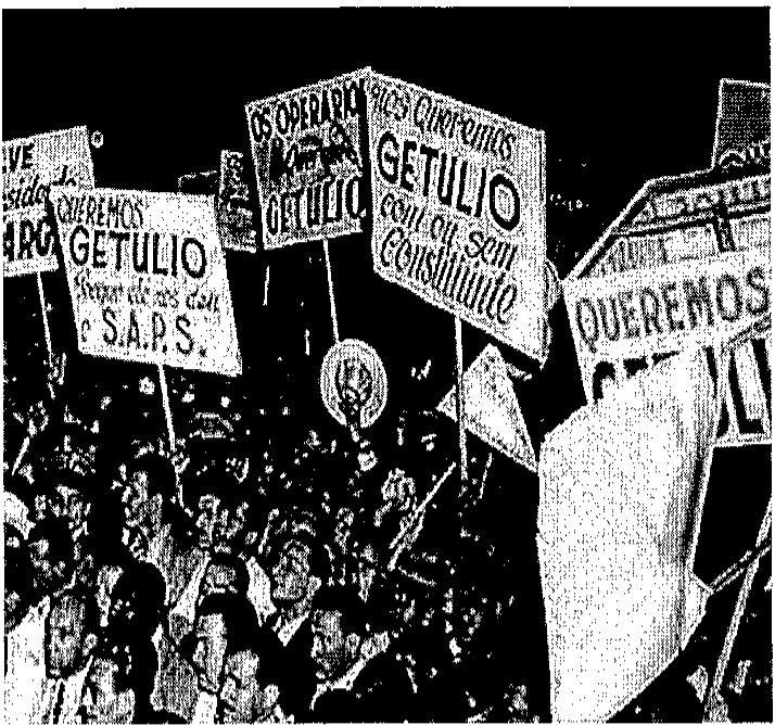 Fotografia em preto e branco de uma multidão em manifestação, com cartazes com dizeres como QUEREMOS GETULIO e QUEREMOS GETULIO COM OU SEM CONSTITUINTE.