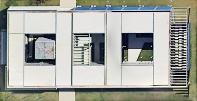 Imagem de satélite, vista de cima, de um prédio retangular claro com três pátios internos e uma escada à direita.