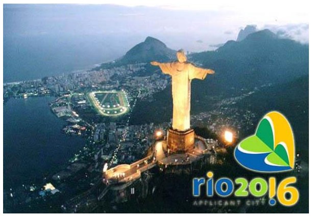 Fotografia noturna do Cristo Redentor iluminado, com vista da cidade do Rio de Janeiro e o logotipo da candidatura Rio 2016.