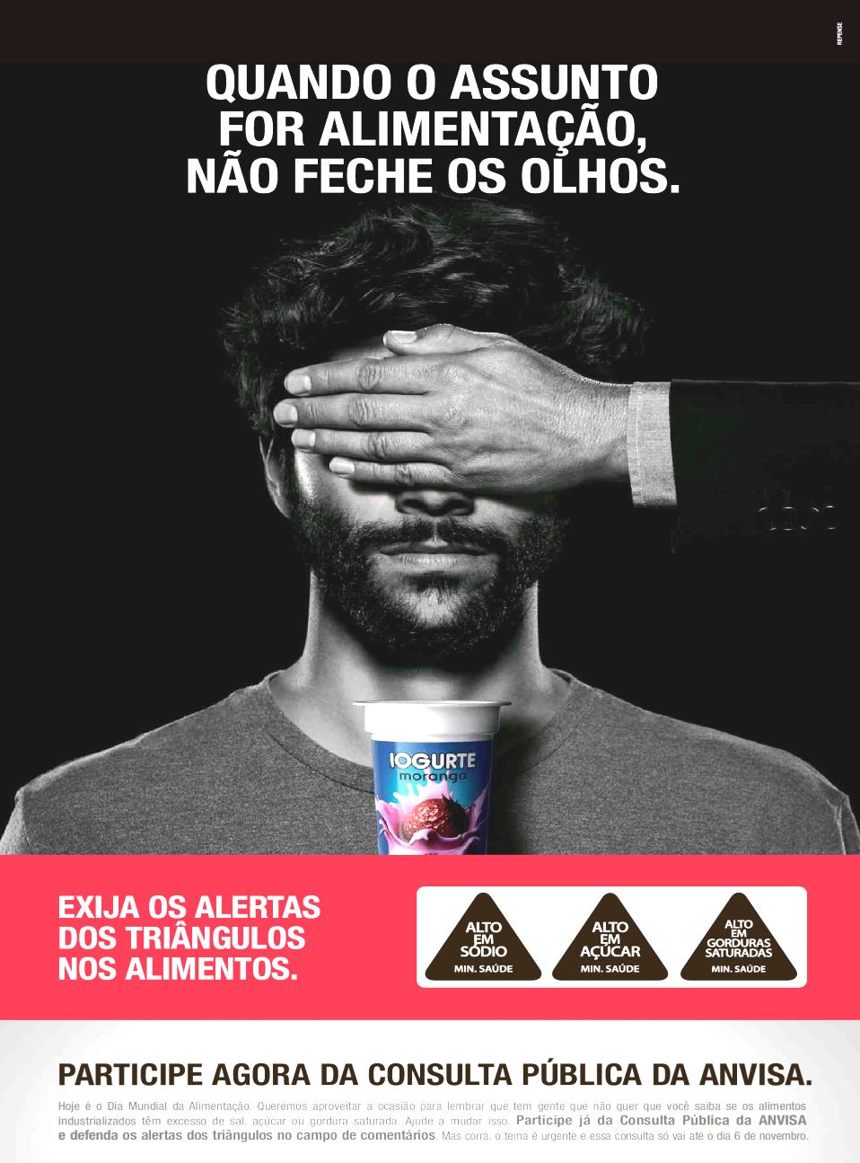Anúncio publicitário em preto e branco: um homem tem os olhos tapados por uma mão e segura um copo de iogurte de morango. Título: “Quando o assunto for alimentação, não feche os olhos.” Faixa vermelha: “Exija os alertas dos triângulos nos alimentos.”, com três triângulos “Alto em sódio”, “Alto em açúcar” e “Alto em gorduras saturadas — Min. Saúde”. Rodapé: “Participe agora da consulta pública da ANVISA.”, seguido de texto pequeno sobre o Dia Mundial da Alimentação e a consulta pública sobre os alertas dos triângulos.
