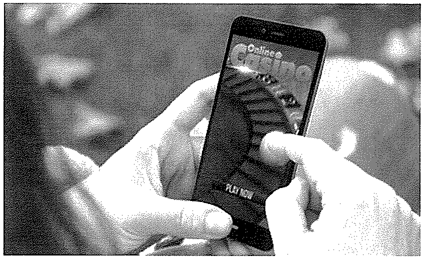 Fotografia: mãos segurando um celular cuja tela exibe um jogo de cassino online (letreiro “Online Casino” e botão “PLAY NOW”, pouco nítidos na digitalização).