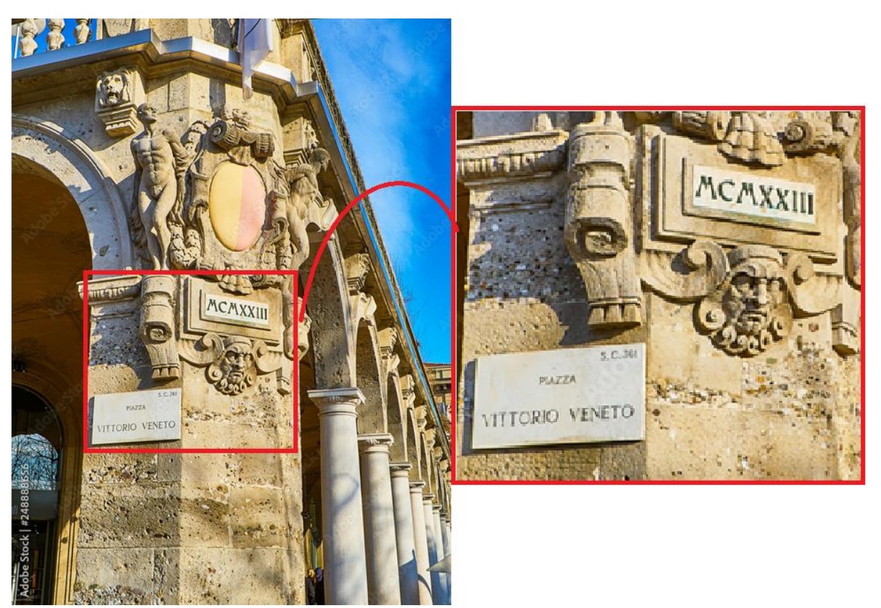 Fotografia de um edifício histórico na Praça Vittorio Veneto, com destaque ampliado de uma placa em pedra com a inscrição em algarismos romanos MCMXXIII, acima de uma placa com os dizeres “Piazza Vittorio Veneto”.