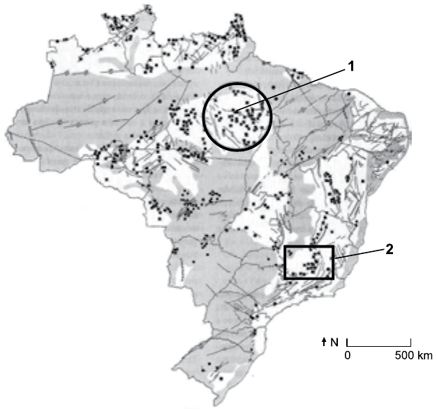 Mapa do Brasil com recursos minerais representados por pontos e manchas cinza, escala de 0 a 500 km e seta do norte. Um círculo marcado com o número 1 destaca uma concentração de pontos no sudeste do Pará; um retângulo marcado com o número 2 destaca uma concentração de pontos no centro-sul de Minas Gerais.