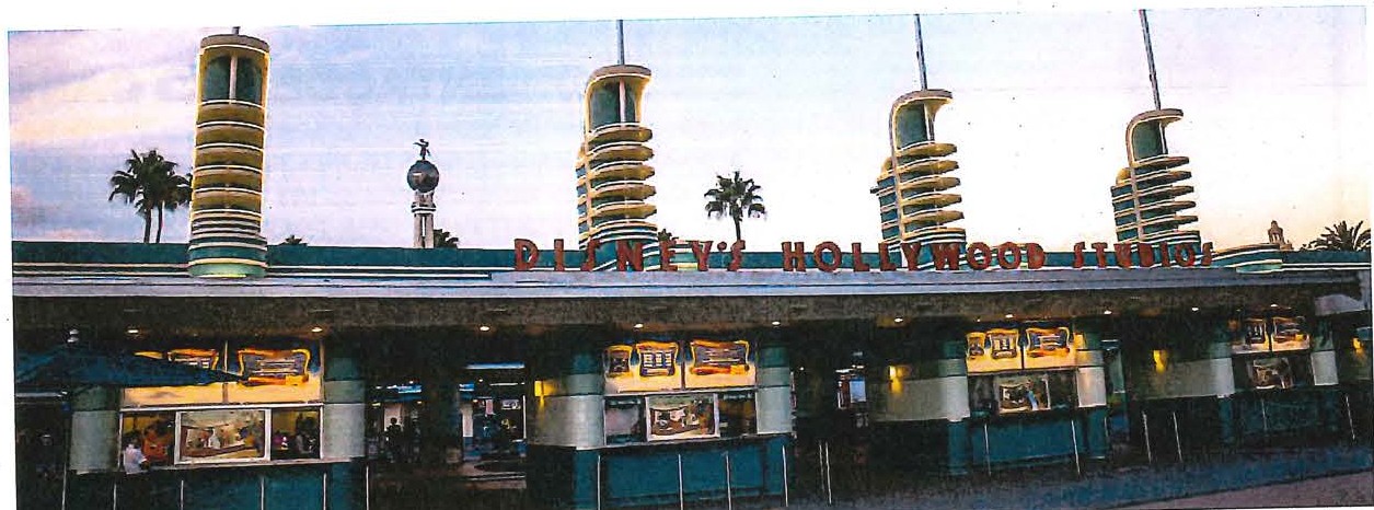 Fotografia da entrada do parque Disney's Hollywood Studios, com torres decorativas e bilheterias sob o letreiro do parque.