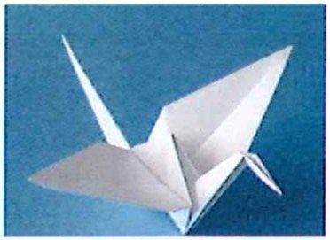 Fotografia de um pássaro de origami (tsuru) branco sobre fundo azul.