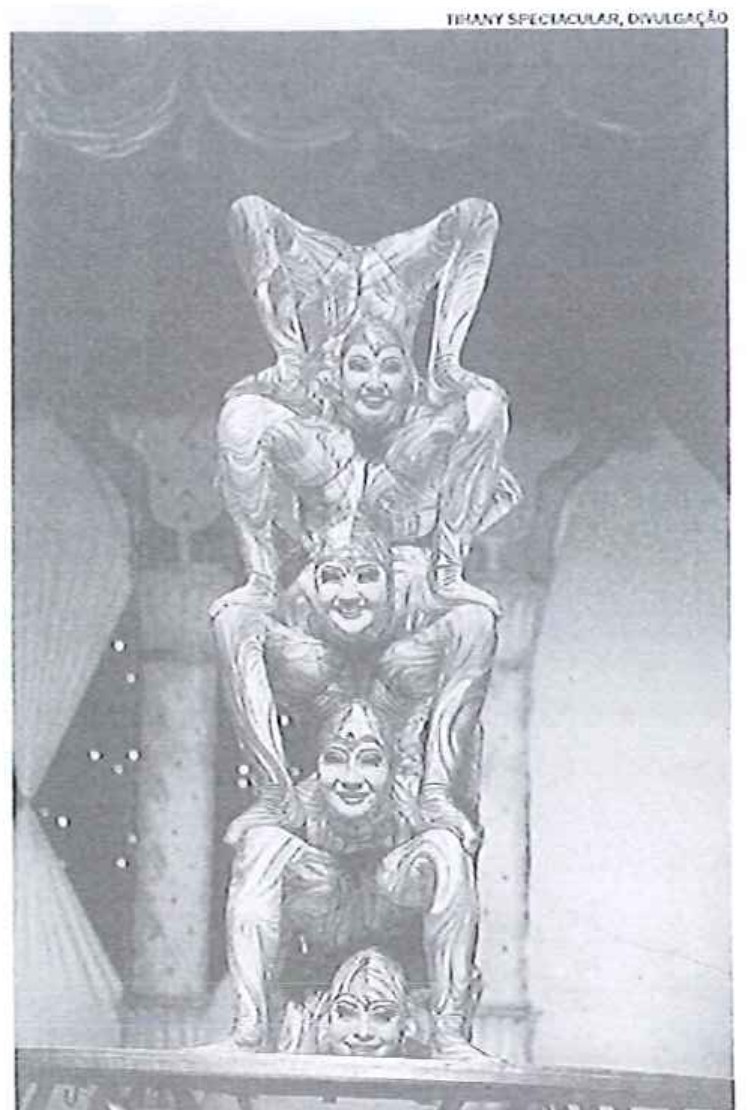 Fotografia em preto e branco de acrobatas do circo Tihany empilhados verticalmente em contorcionismo; crédito no canto: Tihany Spectacular, divulgação.