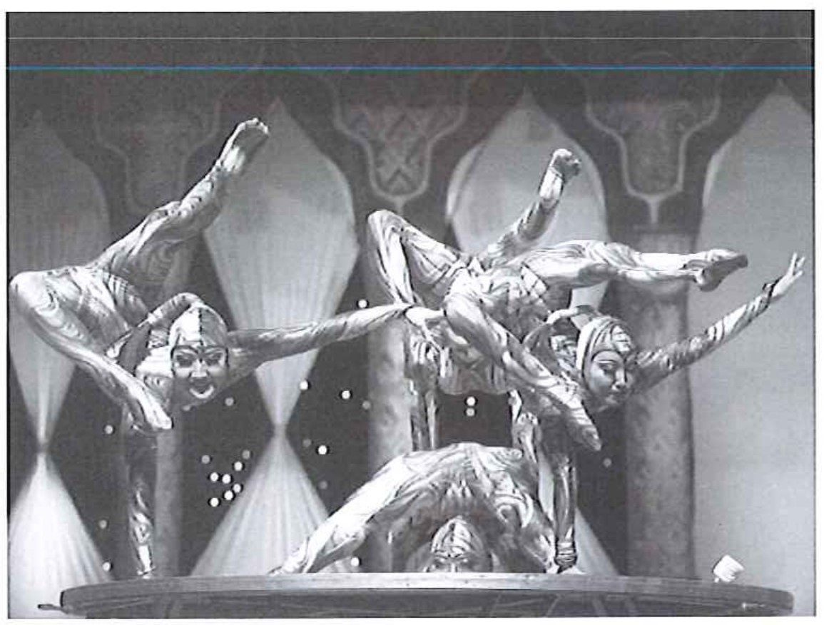 Fotografia em preto e branco de contorcionistas fantasiados do circo Tihany em apresentação sobre um palco, com cenário de arcos ao fundo.
