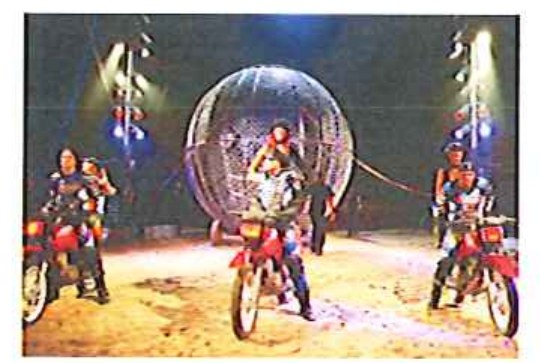 Fotografia de motociclistas com motos vermelhas no picadeiro diante de um globo da morte.