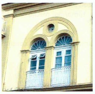 Fotografia de uma fachada do Colégio Militar de Porto Alegre com duas janelas em arco sob um arco maior e uma pequena abertura circular entre elas.