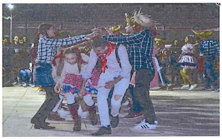 Fotografia de alunos com trajes típicos dançando quadrilha na festa junina do CMSM, à noite.