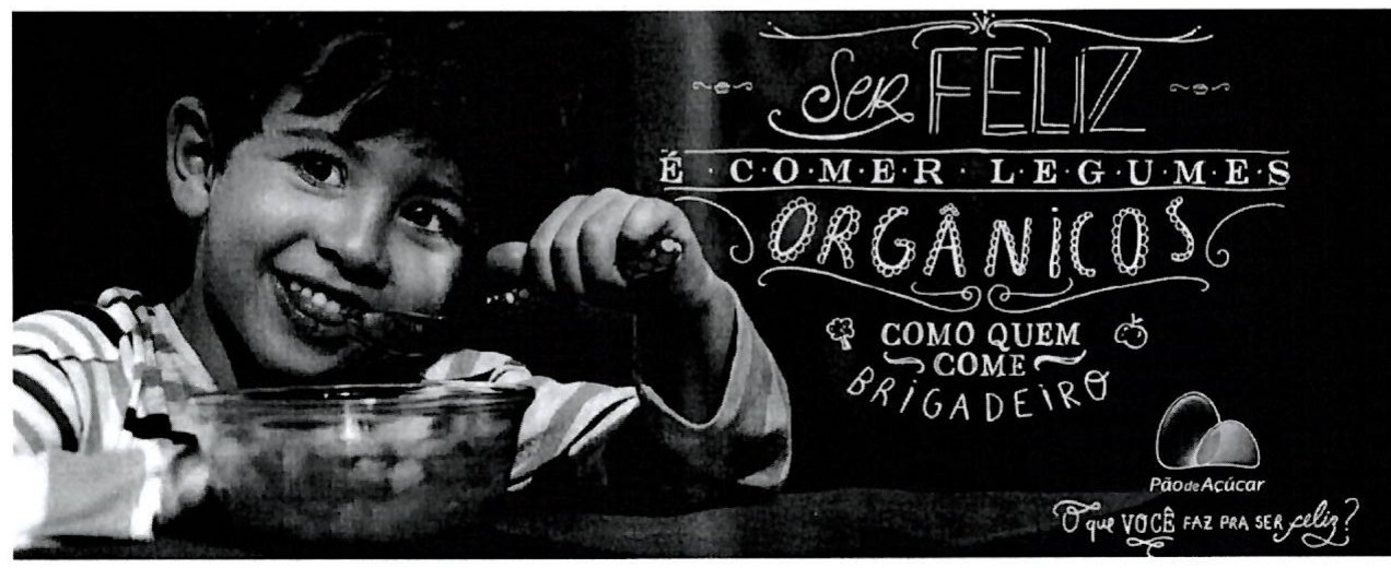 Propaganda do Pão de Açúcar: um menino sorridente come de uma tigela. Texto: 'Ser feliz é comer legumes orgânicos como quem come brigadeiro'. Abaixo, a marca Pão de Açúcar e a frase 'O que você faz pra ser feliz?'.