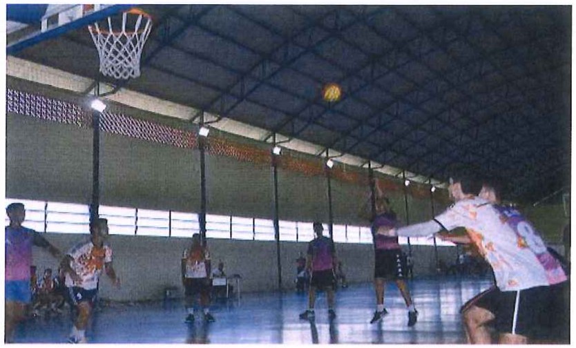 Fotografia de alunos jogando basquete em um ginásio coberto.
