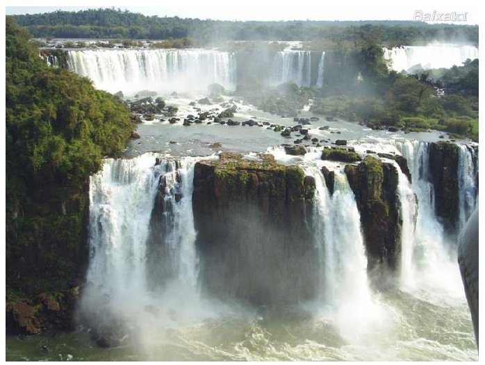 Fotografia das Cataratas do Iguaçu, com várias quedas d'água entre paredões rochosos cobertos de vegetação.