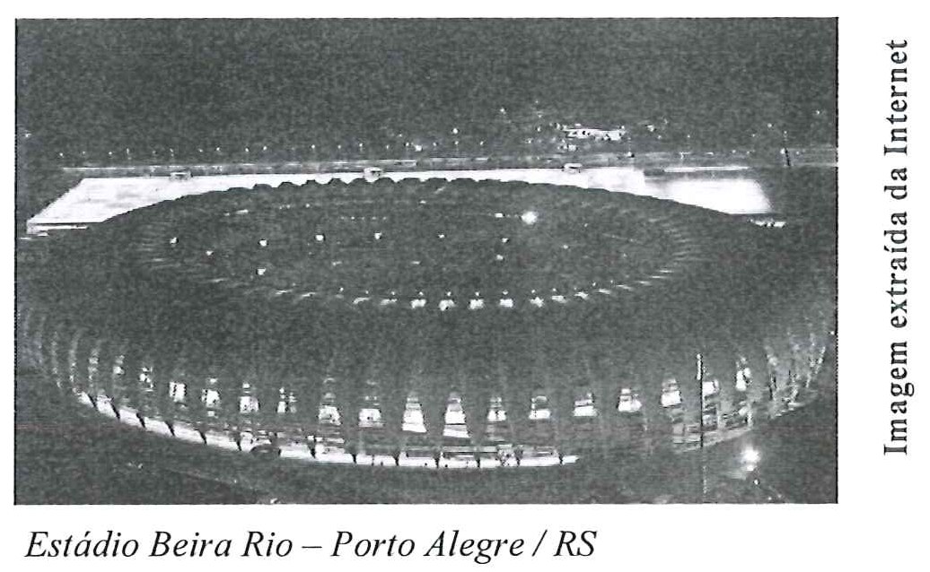 Fotografia noturna aérea do Estádio Beira Rio iluminado, com a legenda impressa "Estádio Beira Rio – Porto Alegre / RS".