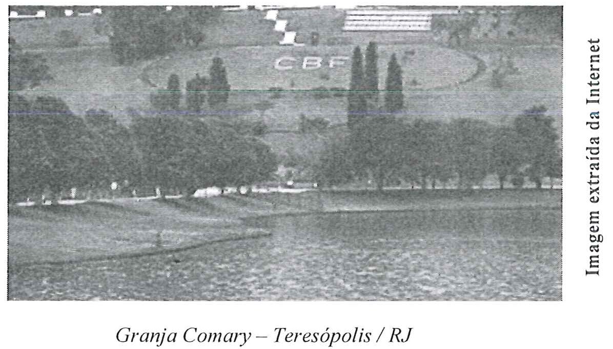 Fotografia da Granja Comary com lago em primeiro plano, árvores e o logotipo CBF no gramado ao fundo, com a legenda impressa "Granja Comary – Teresópolis / RJ".