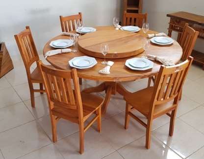 Fotografia de uma mesa redonda de madeira com seis cadeiras e seis pratos dispostos ao redor.