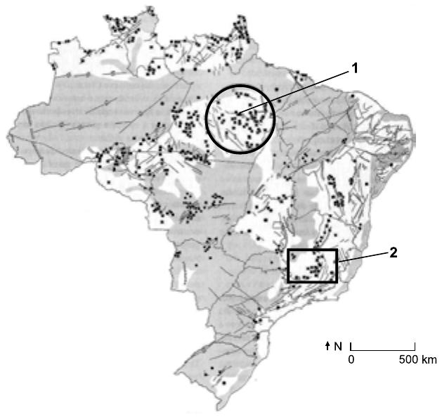 Mapa do Brasil com recursos minerais representados por pontos e manchas cinza, escala de 0 a 500 km e seta do norte. Um círculo marcado com o número 1 destaca uma concentração de pontos no sudeste do Pará; um retângulo marcado com o número 2 destaca uma concentração de pontos no centro-sul de Minas Gerais.