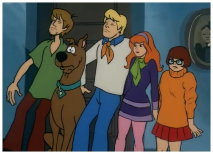 Ilustração do desenho animado Scooby-Doo: o cachorro Scooby, marrom com coleira azul, ao lado dos amigos Salsicha, Fred, Daphne e Velma, todos com expressão assustada, em um corredor.