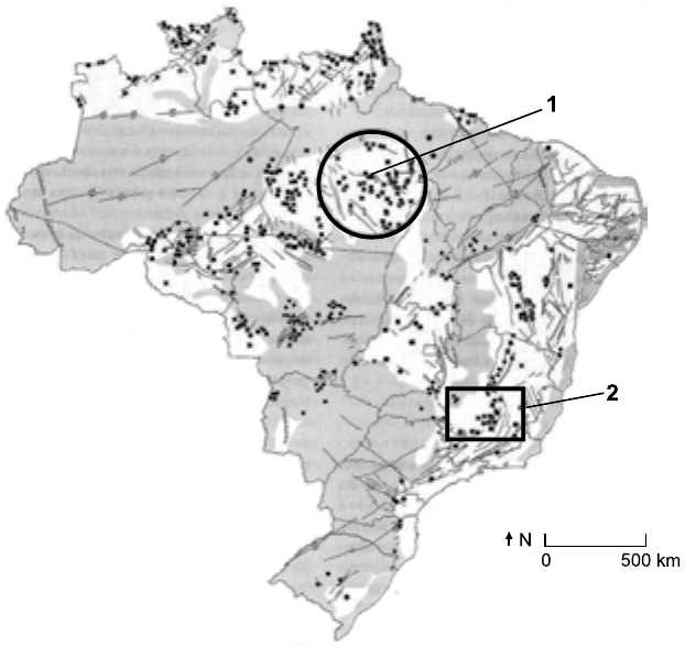 Mapa do Brasil com recursos minerais representados por pontos e manchas cinza, escala de 0 a 500 km e seta do norte. Um círculo marcado com o número 1 destaca uma concentração de pontos no sudeste do Pará; um retângulo marcado com o número 2 destaca uma concentração de pontos no centro-sul de Minas Gerais.