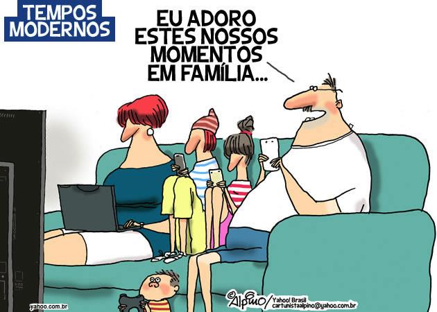 Charge “Tempos modernos”: família sentada em um sofá diante da televisão; a mãe usa um notebook, duas crianças usam celulares, um bebê no chão segura um aparelho, e o pai, também com um celular na mão, diz no balão: “EU ADORO ESTES NOSSOS MOMENTOS EM FAMÍLIA...”.